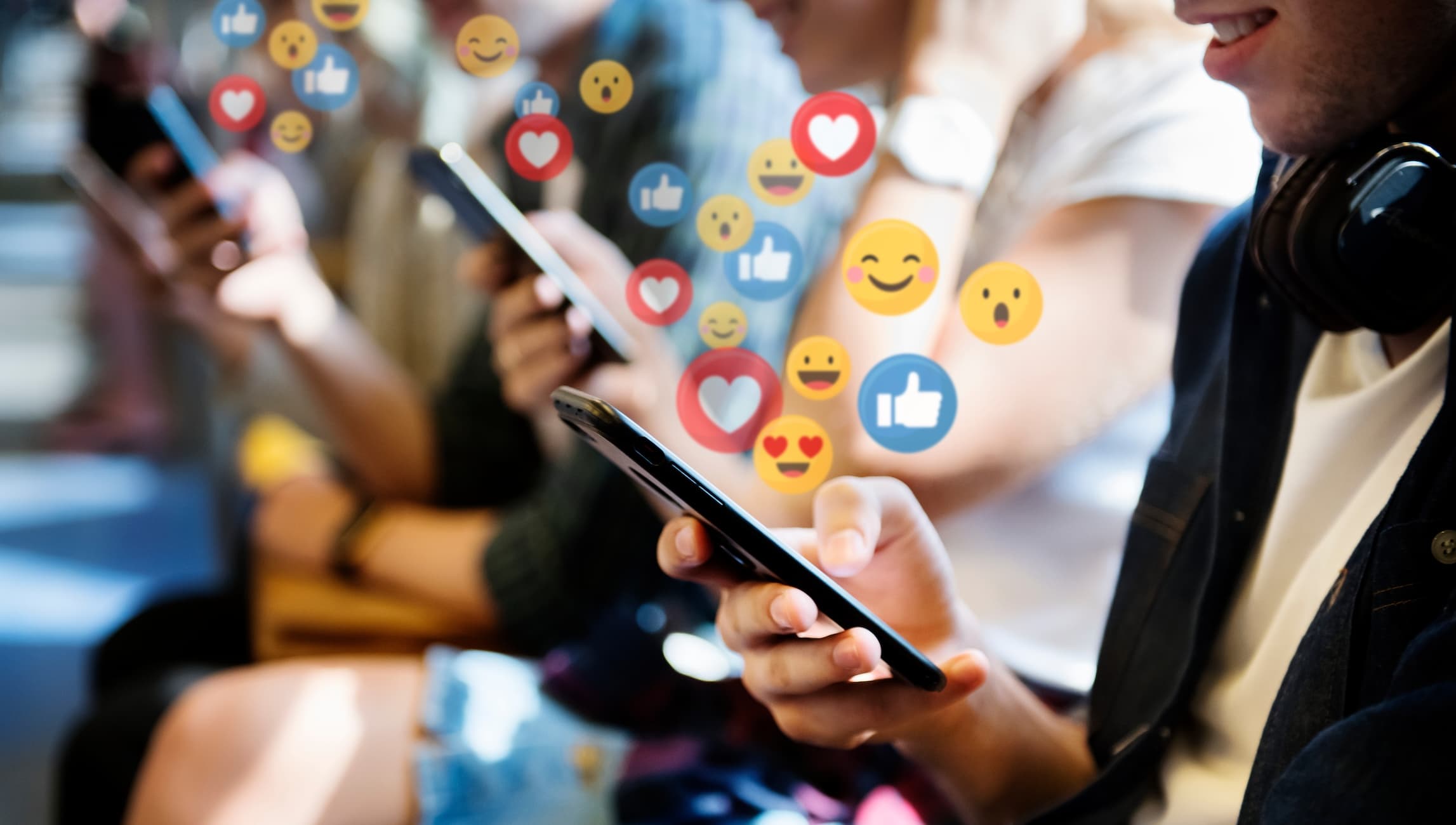 People on phones with social engagement icons floating up — illustrating creator-driven influence in B2B discovery